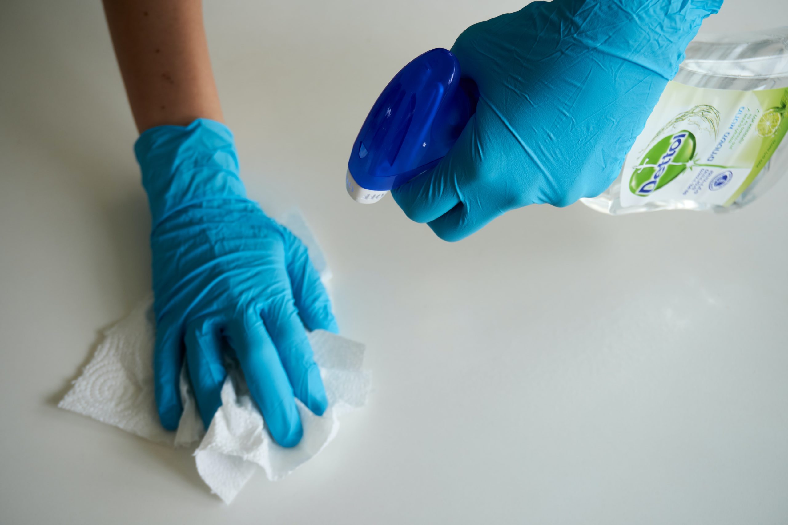 Two hands with gloves cleaning a surface