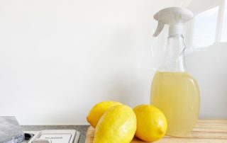 Three lemons and a bottle of cleaning solution sitting on a kitchen counter