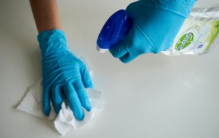 Two hands with gloves cleaning a surface